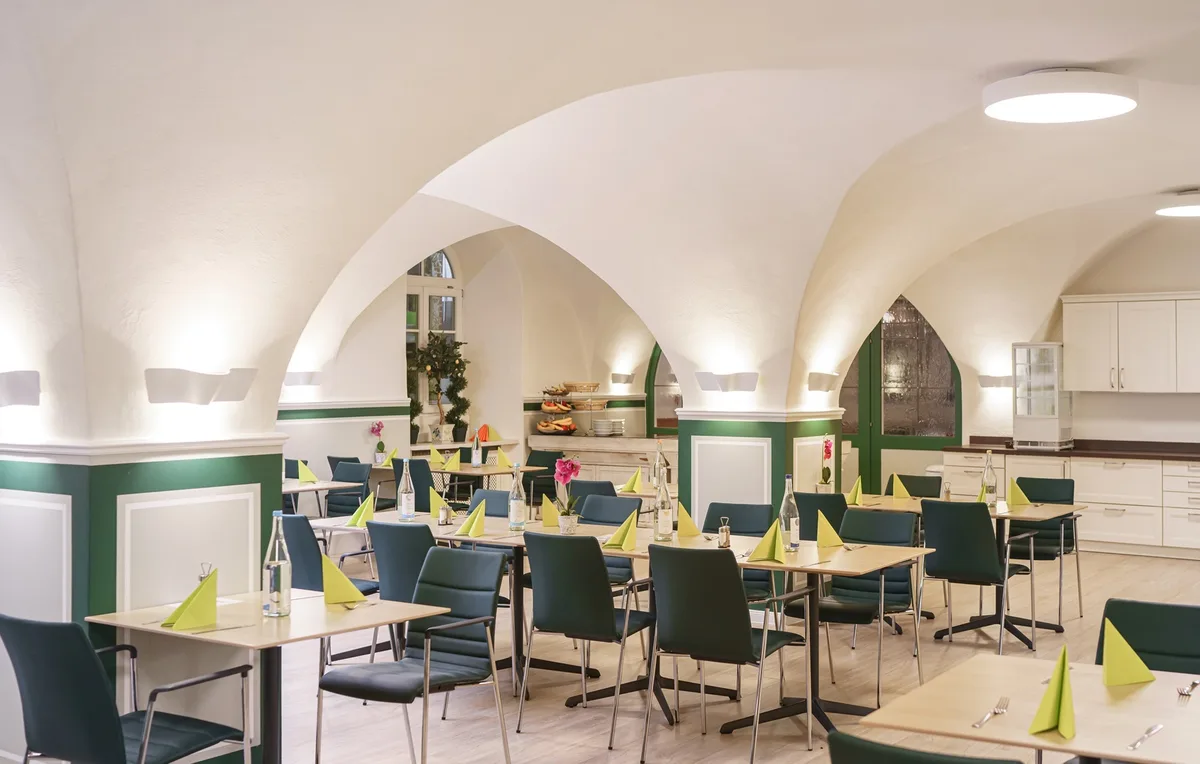 The dining hall with a vaulted ceiling, tables and chairs