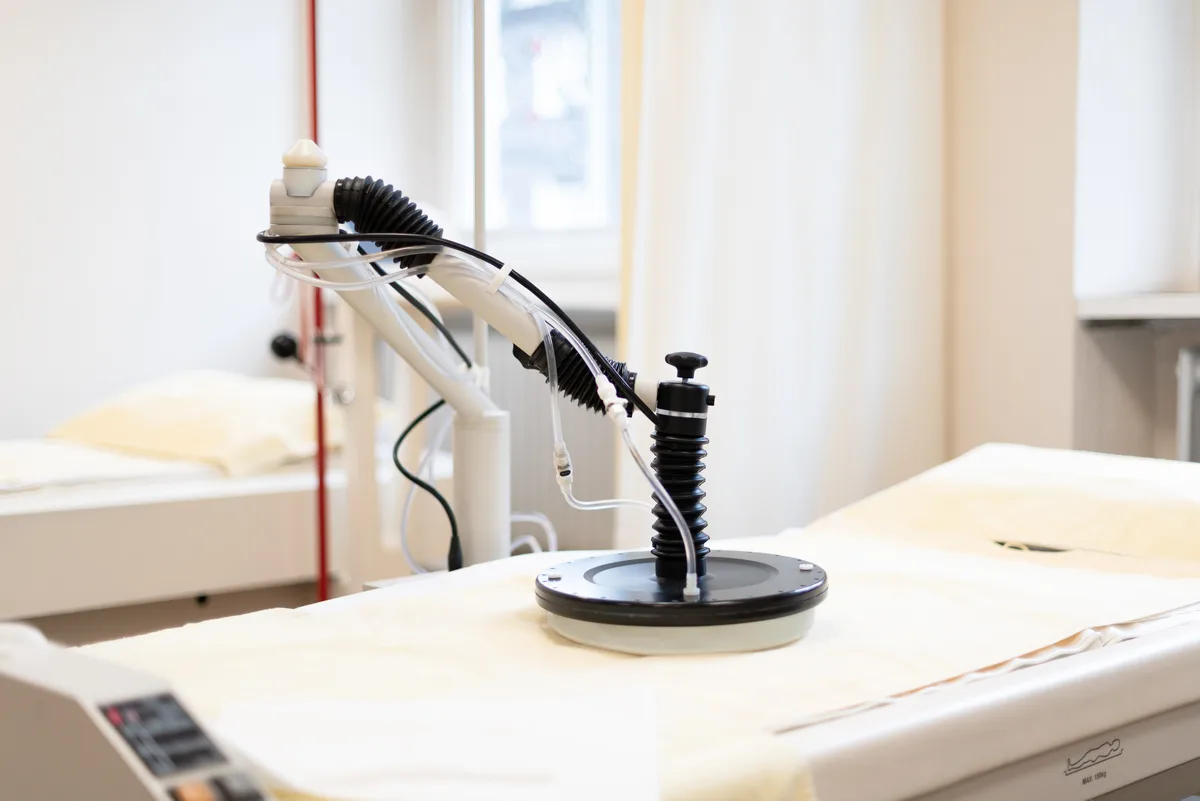 An articulated local hyperthermia applicator arm positioned above a treatment couch in a bright room